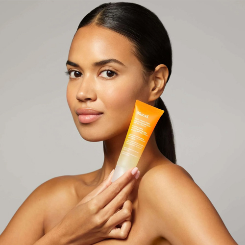 Model houdt de Murad Multi Vitamin Clear Coat SPF 50 zonnebrandcrème vast voor haar gezicht