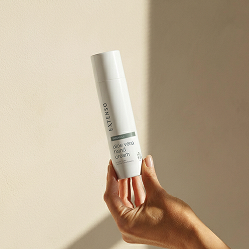 Hand die een tube Extenso Aloë Vera Hand Cream vasthoudt.