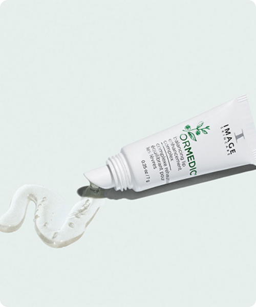 Een tube IMAGE Skincare ORMEDIC Balancing Lip Enhancement Complex waaruit een transparante, glanzende lipverzorging vloeit in een sierlijke vorm.