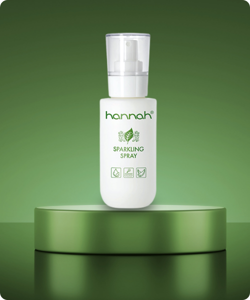 Een witte flacon hannah Sparkling Spray gepresenteerd op een rond groen plateau tegen een matgroene achtergrond.