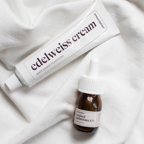 Tube Prescription edelweiss cream en bruin glazen flesje Prescription retinol palmitate op een witte stoffen ondergrond
