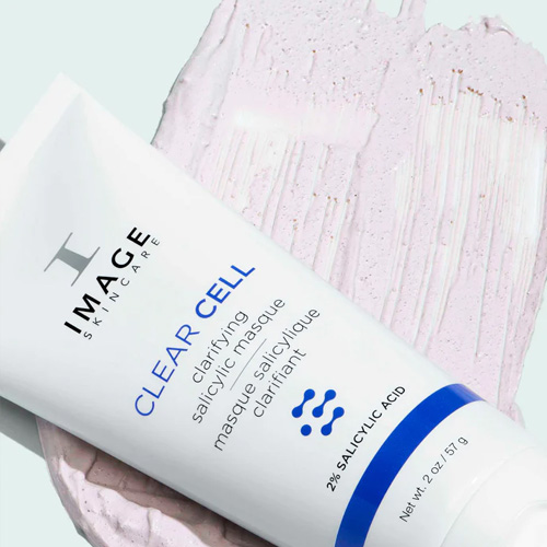 De tube van het IMAGE Skincare Clear Cell masker liggend op een uitgesmeerde laag van de paarse masker-textuur.