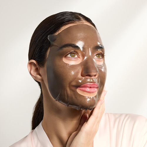 Een vrouw die het donkergrijze, vochtige hydrogel sheetmasker op haar gezicht draagt voor een diepe hydratatie.