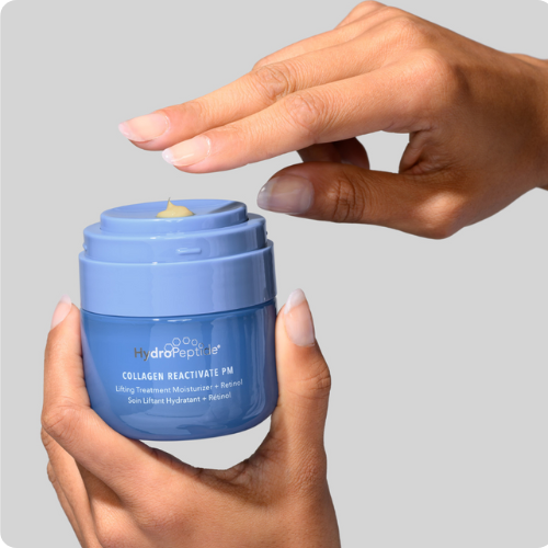 Twee handen houden een blauwe pot HydroPeptide Collagen Reactivate PM nachtcrème vast terwijl een vinger een dosering van de pompapplicator neemt.