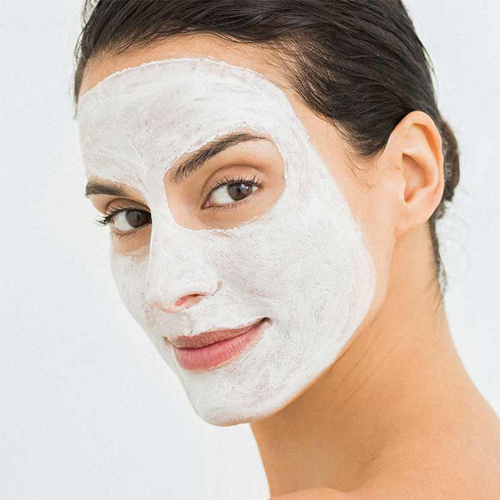 Een vrouw draagt het witte HydroPeptide Miracle Mask gezichtsmasker op haar gezicht voor een verzorgende behandeling.