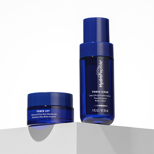 Twee blauwe verzorgingsproducten van HydroPeptide, een Power Serum en een Power Lift moisturizer, staan opgesteld op een witte ondergrond.