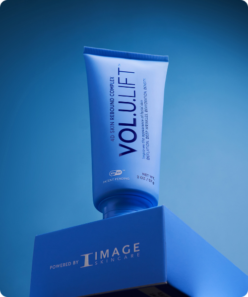 en blauwe tube van IMAGE Skincare VOL.U.LIFT 4D Skin Rebound Complex die rechtop staat op een bijbehorend blauw doosje met het logo van IMAGE Skincare.