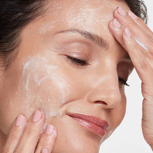 Persoon die de HydroPeptide Exfoliating Cleanser aanbrengt op het gezicht tijdens de gezichtsreiniging.