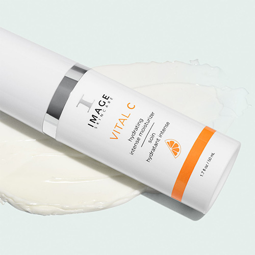 De Hydrating Intense Moisturizer flacon liggend op een grote swatch van de witte crème.