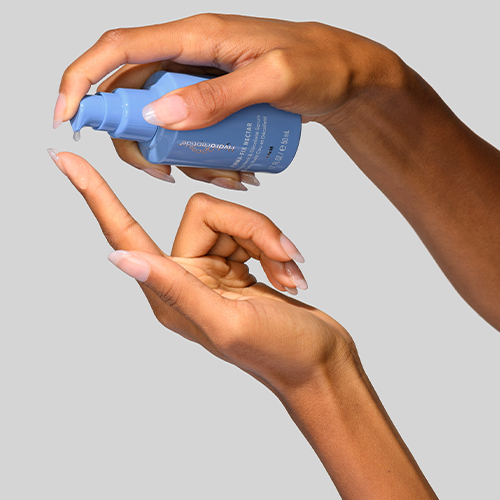 Iemand pompt een druppel van het HydroPeptide Firma Fix Nectar serum uit de blauwe flacon op de vinger.