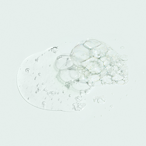 Een close-up van de vloeibare textuur van de IMAGE MD Restoring Facial Cleanser op een lichte ondergrond.