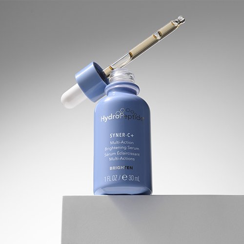 HydroPeptide Syner C+ serumflacon van 30ml met de open pipet ernaast op een witte verhoging