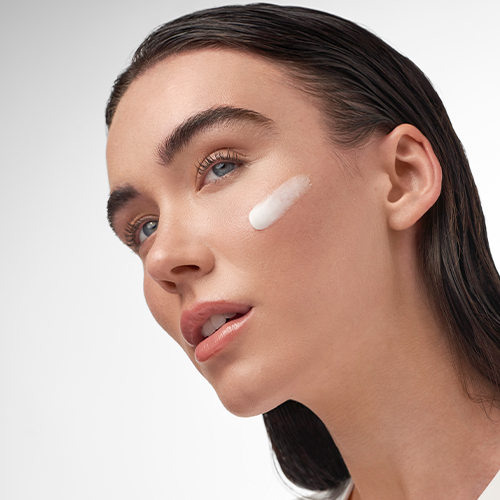 Zijaanzicht van een model met een veeg van de witte IMAGE Skincare IMAGE MD recovery balm op haar jukbeen voor een hydraterend effect.