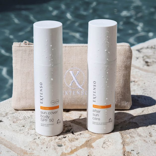 Sfeerbeeld van de Extenso Sun Cover SPF 50 en After Sun flacons met waterdruppels, staand op een stenen rand naast een zwembad met een beige etui op de achtergrond.
