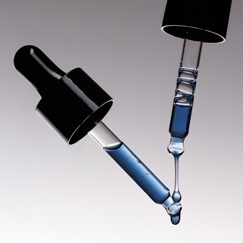 Close-up van twee glazen pipetten die de helderblauwe, vloeibare textuur van het AlgiZome boosterserum tonen.