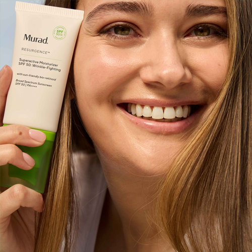 Lachend model houdt een tube Murad Superactive Moisturizer SPF 50 vast