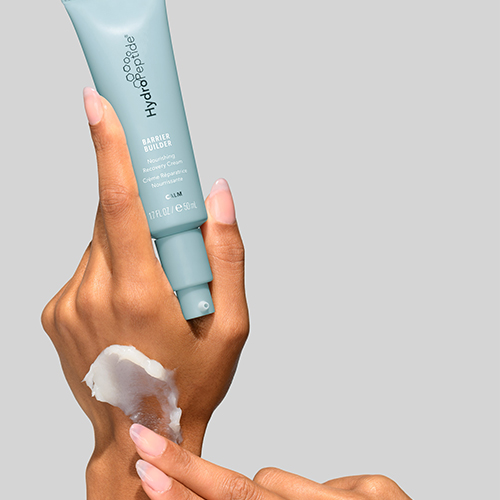 Handen die de HydroPeptide Barrier Builder herstellende crème aanbrengen op de huid met zichtbare textuur