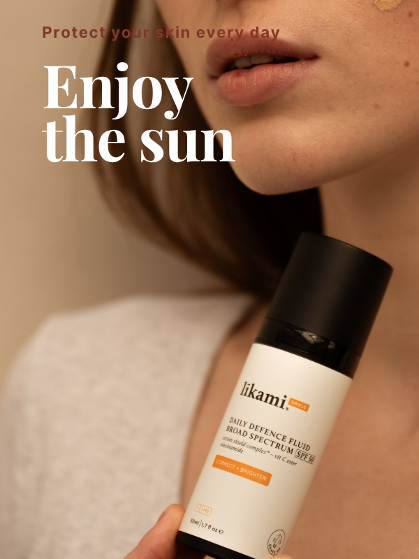 Een vrouw houdt een fles Likami Daily Defence Fluid SPF 50 vast. De tekst op de afbeelding luidt: "Protect your skin every day. Enjoy the sun."