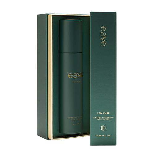 De Eave I AM PURE Face Cleanser staat in de geschenkverpakking op een witte achtergrond. De doos is donkergroen met goudkleurige letters en een verticale gouden streep. De fles is zichtbaar in de doos.