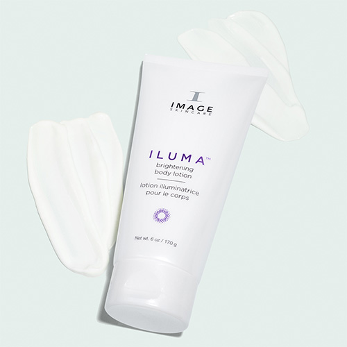 De grote witte tube van de Iluma Brightening Body Lotion ligt horizontaal op een decoratieve uitsmering van de lotion op een lichtblauwe achtergrond.