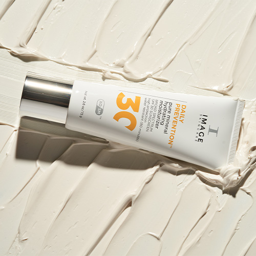 De witte tube van de Pure Mineral Hydrating Moisturizer liggend op een dikke, uitgesmeerde laag witte crème.