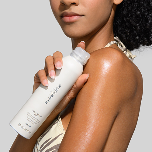 Een model brengt HydroPeptide Solar Defense Body SPF 30 zonnebrand aan op haar schouder