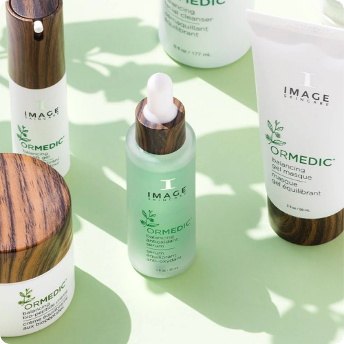 Een zij-bovenaanzicht van de IMAGE Skincare ORMEDIC collectie, met de focus op het Balancing Antioxidant Serum en de Bio-Peptide Cream tegen een frisse, lichtgroene achtergrond.