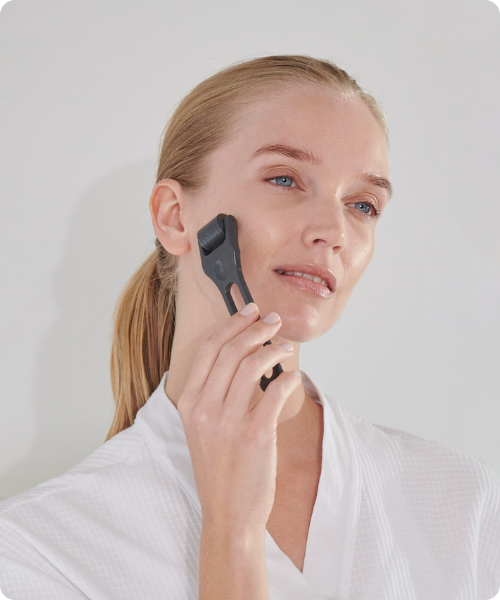 Een vrouw gebruikt de donkergrijze Environ Cosmetic Roll-CIT roller op haar wang