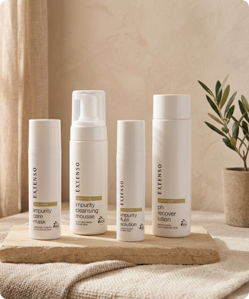 Vier witte flessen en pompverpakkingen uit de Extenso Clear Skin lijn staan op een natuurstenen plateau in een rustieke omgeving met een olijfboom op de achtergrond.
