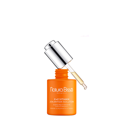 Het geopende flesje van Natura Bissé Antiox Solution waarbij de zilveren druppelaar schuin boven de opening rust en een druppel serum laat zien.