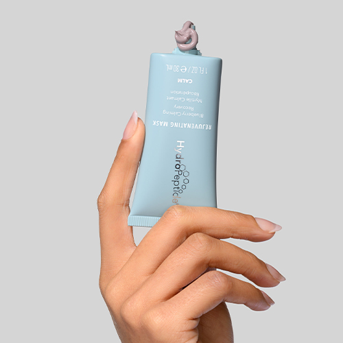 Hand die een tube HydroPeptide Rejuvenating Mask vastheeft met een beetje masker op de dop