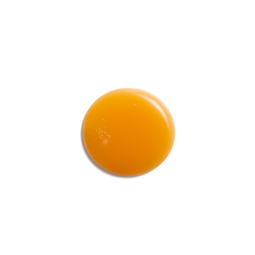 Een close-up van een ronde druppel van het Natura Bissé Stabilizing Purifying Concentrate, die een heldere oranje kleur en vloeibare textuur heeft.