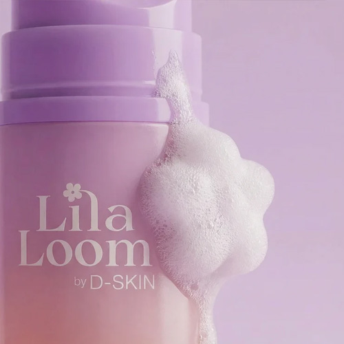 Close-up van de Lila Loom Daily Bloom Cleanser flacon met wit, luchtig reinigingsschuim dat in een bloemvorm aan de zijkant van de dop zit.