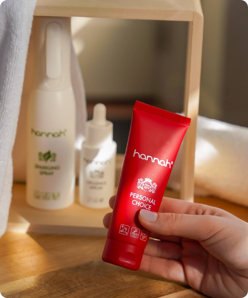 Een tube hannah Personal Choice huidverzorging gepresenteerd op een rood podium tegen een achtergrond in bijpassende rode tinten.