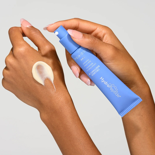 Een model brengt de HydroPeptide Collagen ReActivate AM aan vanuit een blauwe tube op de rug van de hand.
