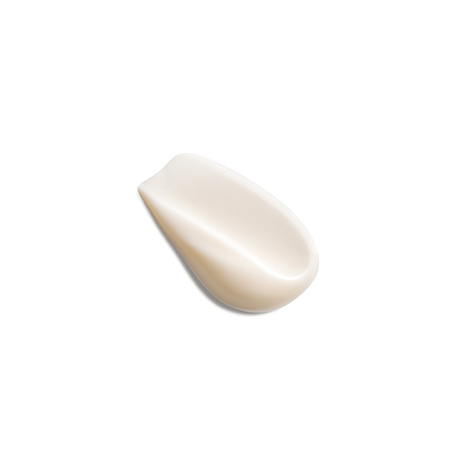 Een swatch van een romige, licht beige cosmetische crème, aangebracht op een witte achtergrond. De swatch heeft een gladde, golvende textuur en een lichte schaduw.