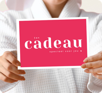 Een persoon in een witte badjas houdt een opvallende roze kaart vast met de tekst Een cadeau speciaal voor jou, wat staat voor een hannah cadeaubon. De achtergrond is effen en licht.