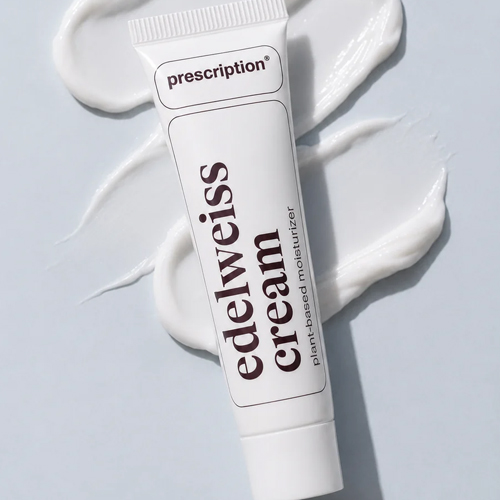 Een tube Prescription edelweiss cream plant based moisturizer geplaatst op uitgesmeerde witte crème op een lichtblauwe ondergrond