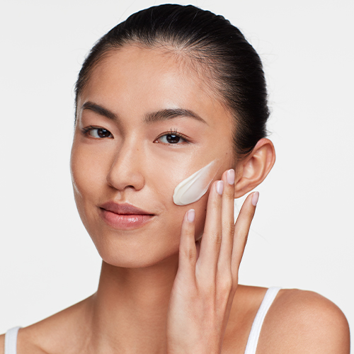 Een jonge vrouw brengt HydroPeptide Power Lift aan op haar jukbeen met een lichte, egale textuur.
