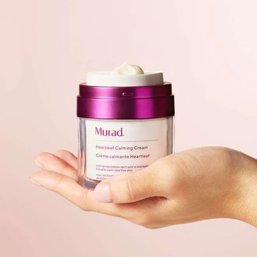 Hand met een open pot Murad Heartleaf Calming Cream met een beetje crème op de opening