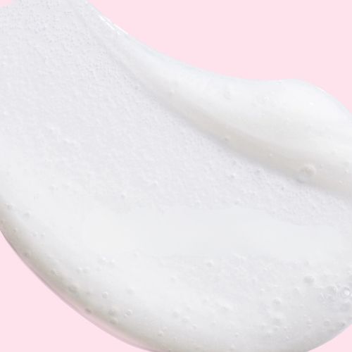 Witte schuimende textuur van de Murad Hydration reinigingscrème op een roze achtergrond