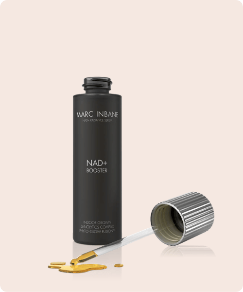 Een zwarte flacon van Marc Inbane NAD+ Booster serum met een losgedraaide pipet en een druppel goudkleurige vloeistof op een neutrale ondergrond.