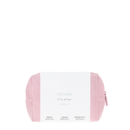Een productfoto van de Darling A la plage Summer Kit. De set wordt gepresenteerd als een roze, wafel geweven toilettas met daaroverheen een witte wikkel met de productinformatie.