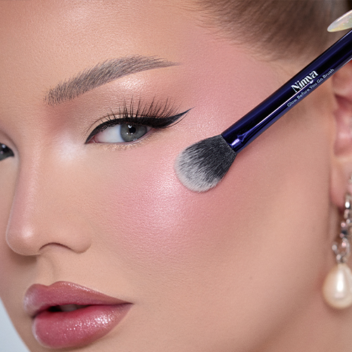 Gedetailleerd overzicht van de applicatie van blush en highlighter op de wang met de blauwe Nimya kwast.