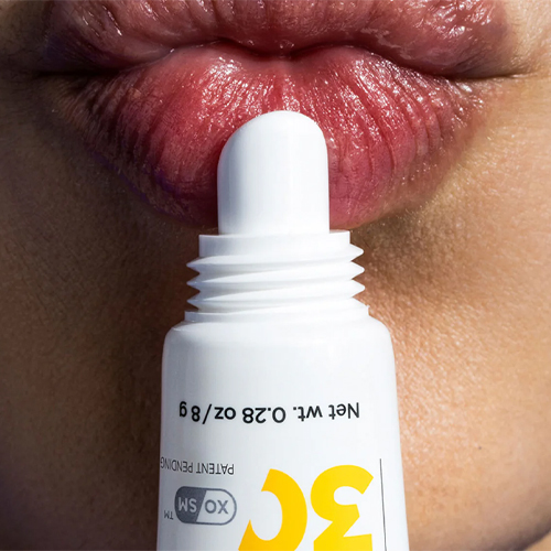 Close-up van de witte applicator van de Daily Prevention Nourishing Lip Balm die wordt aangebracht op de lippen voor hydratatie en bescherming.