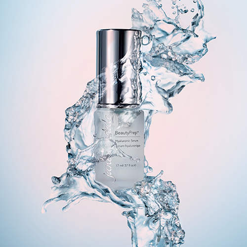 Artistiek sfeerbeeld van het jane iredale Hyaluronic Serum omringd door dynamische waterspetters, wat symbool staat voor intense hydratatie.