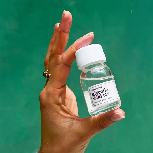 Hand die een flesje prescription glycolic acid 10 procent vasthoudt voor een groene achtergrond