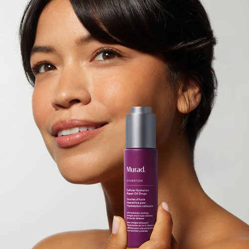 Vrouw houdt de fles Murad Cellular Hydration Repair Oil Drops tegen haar gezicht