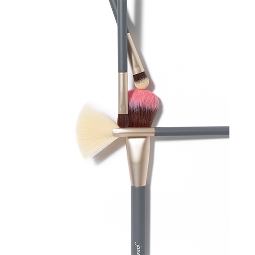 Sfeerfoto van Jane Iredale kwasten op een witte achtergrond met roze poedertint.