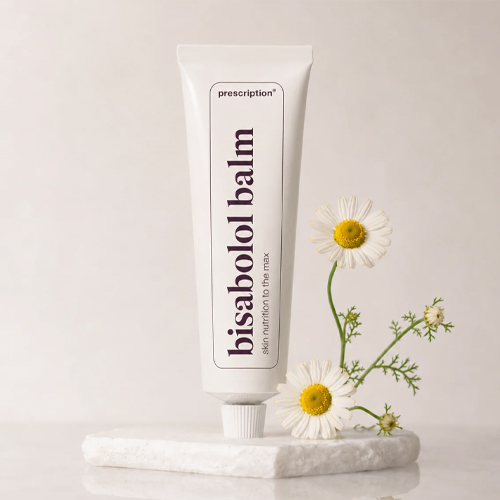 Witte tube Prescription bisabolol balm op een sokkel met kamillebloemen